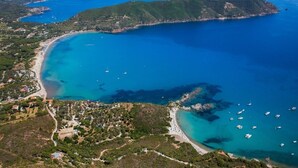 An aerial view of a coastal area with a beach, boats, and a mountainous landscape. - Fantastic sea view and privacy (Lacona)