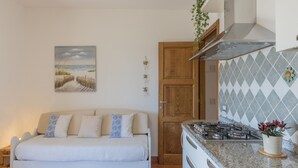 A cozy room with a bed, a kitchen with a gas stove, and a door leading to another room. - Fantastic sea view and privacy (Lacona)
