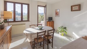 A dining area with a table, chairs, a lamp, a radiator, a television, and a framed picture on the wall. - Spacious, bright and comfortable with 2 terraces (Portoferraio)