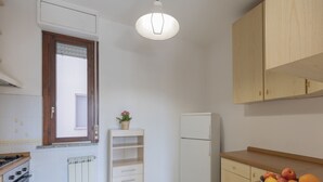 A compact kitchen with a built-in oven, a white refrigerator, wooden cabinets, and a window with a view. - Spacious, bright and comfortable with 2 terraces (Portoferraio)