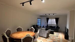 Un amplio espacio de sala con una mesa de comedor, sofás y una televisión.
