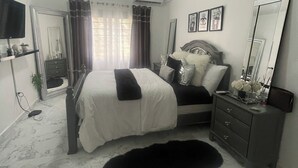 A bedroom with a bed, a dresser, a mirror, and a television. - Modern Ocean View Apartment (Pointe Blanche)