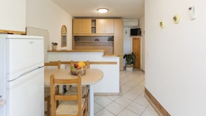 A compact kitchen with a central island, wooden cabinets, and a tiled floor. - Quiet, well-kept stay for couples or families (Campo nell'Elba)