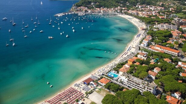 An aerial view of a coastal town with a beach, boats, and buildings. - Quiet, well-kept stay for couples or families (Campo nell'Elba)