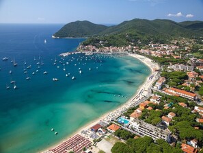 An aerial view of a coastal town with a beach, boats, and buildings. - Quiet, well-kept stay for couples or families (Campo nell'Elba)
