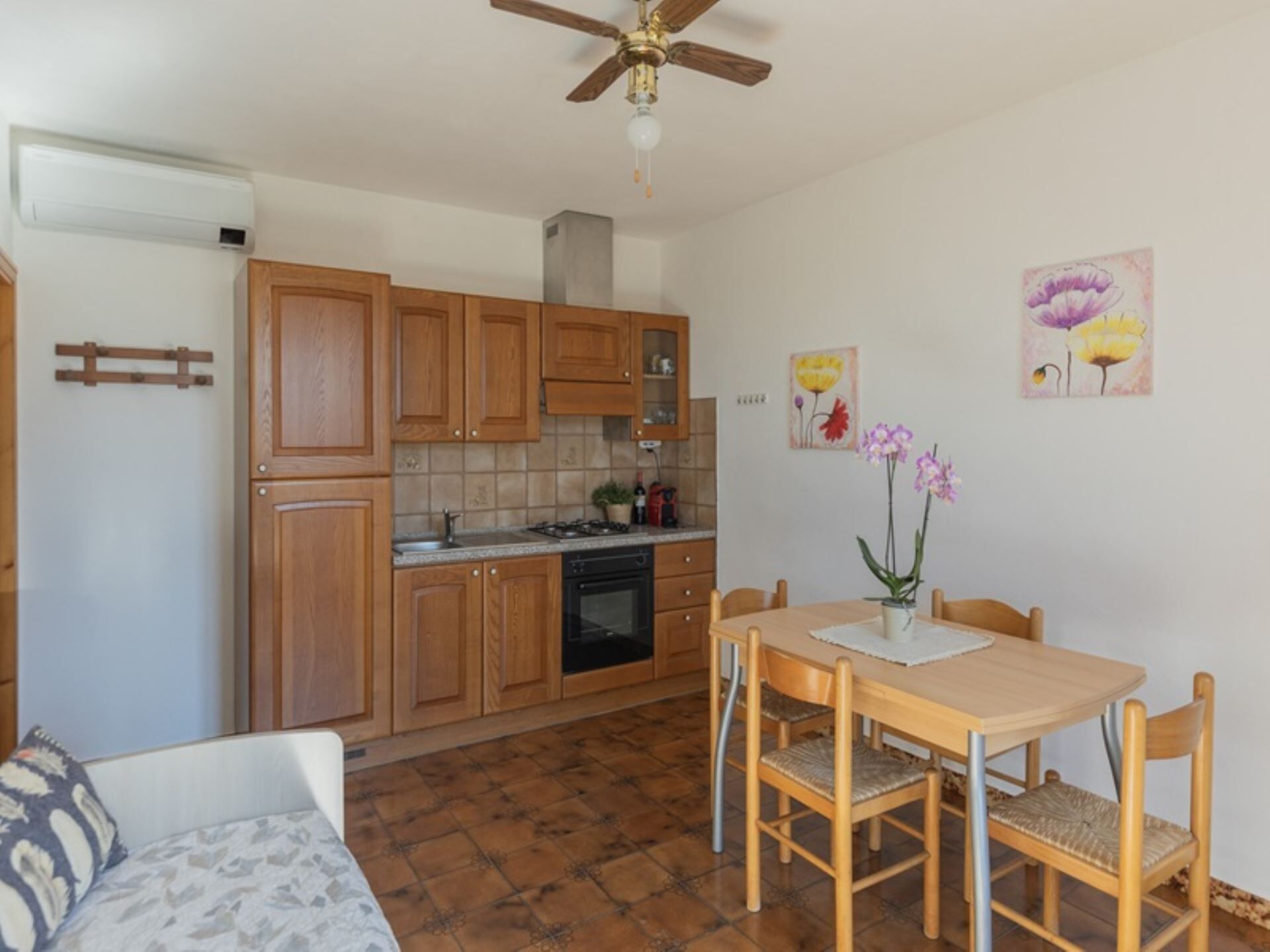 A compact kitchen with wooden cabinets, a gas stove, and a ceiling fan.