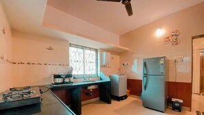 Una cocina con mostrador negro, refrigerador, pileta y ventana con barandillas decorativas.