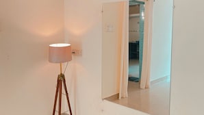 Una habitación con una lámpara de pie, un espejo grande y un cuadro de caballos.