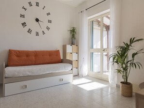 A modern living room with a sofa, a wall clock, a potted plant, and a sliding glass door. - Large terrace with view over the Gulf of Lacona (Lacona)