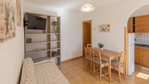 Ett kompakt bostadsutrymme med en matplats, ett litet kök och en soffa.