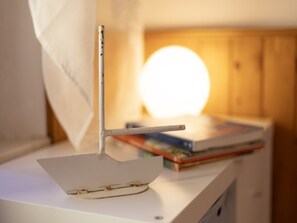 A model ship on a white surface with a blurred background featuring a round light source and stacked books. - Apartment with garden and BBQ near the sea (Lacona)