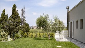 A well-maintained garden with a lawn, trees, and a building with a chimney.