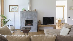 A living room with a fireplace, a television, and a dining area.