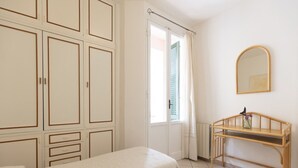A bedroom with two beds, a wooden desk, a mirror, and a wardrobe. - In the center, 100 meters from the sea! (Marina di Campo)