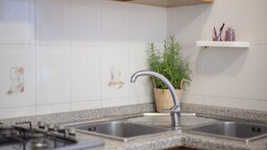 A kitchen with a granite countertop, stainless steel sink, and a gas stove. - In the center, 100 meters from the sea! (Marina di Campo)