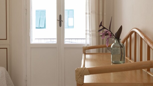 A room with a wooden table, a glass vase with flowers, and a window with curtains. - In the center, 100 meters from the sea! (Marina di Campo)