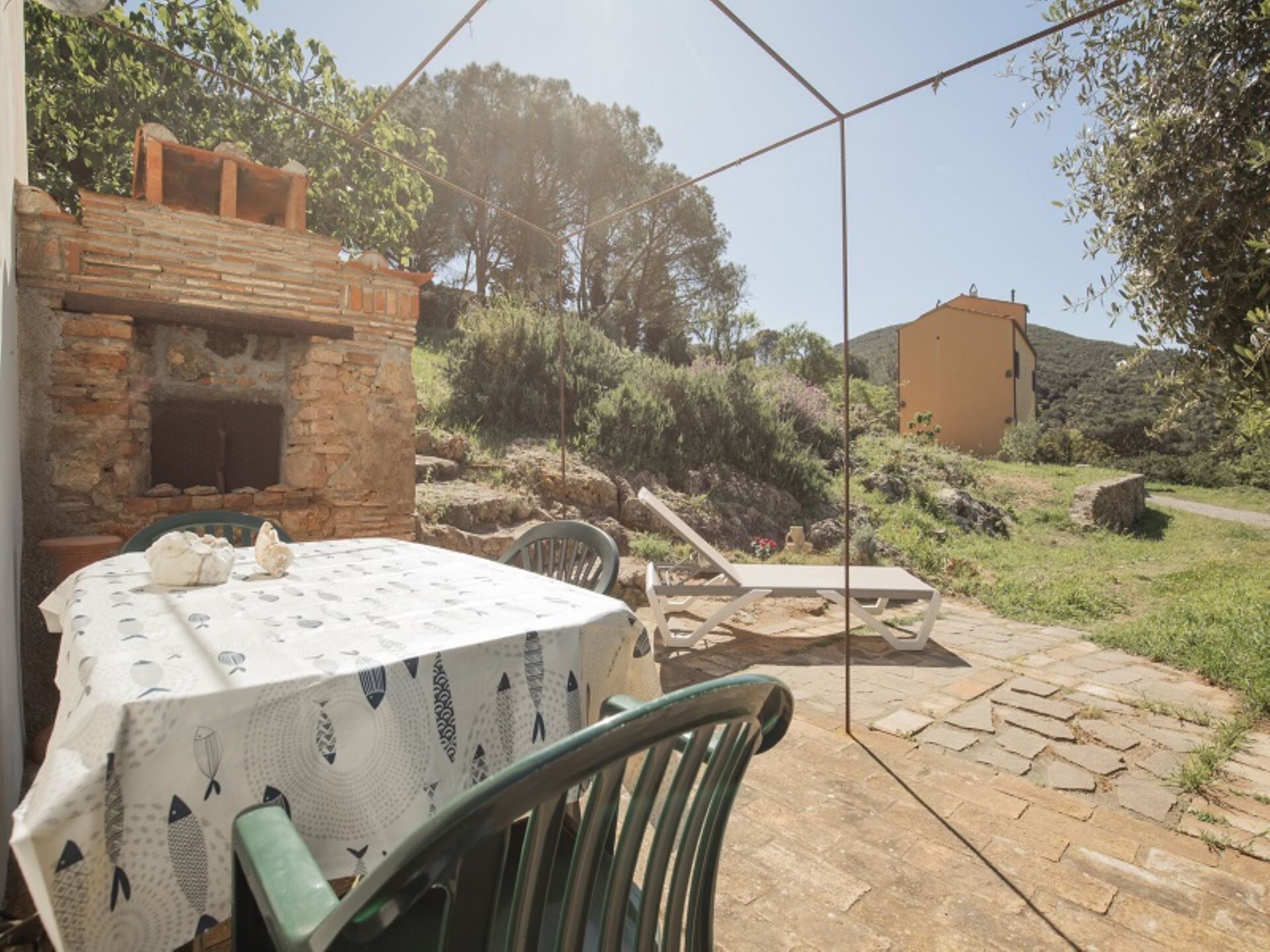 A patio with a table set for dining, a brick oven, and a stone pathway leading to a building.