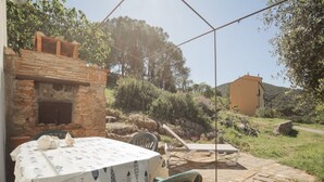 A patio with a table set for dining, a brick oven, and a stone pathway leading to a building. - Perfect for couples, independent and on two levels (Rio Marina)