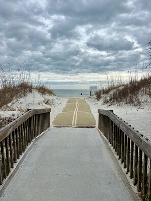 Ein Weg, der zu einem Strand führt, gesäumt von einem Holzzaun auf beiden Seiten.