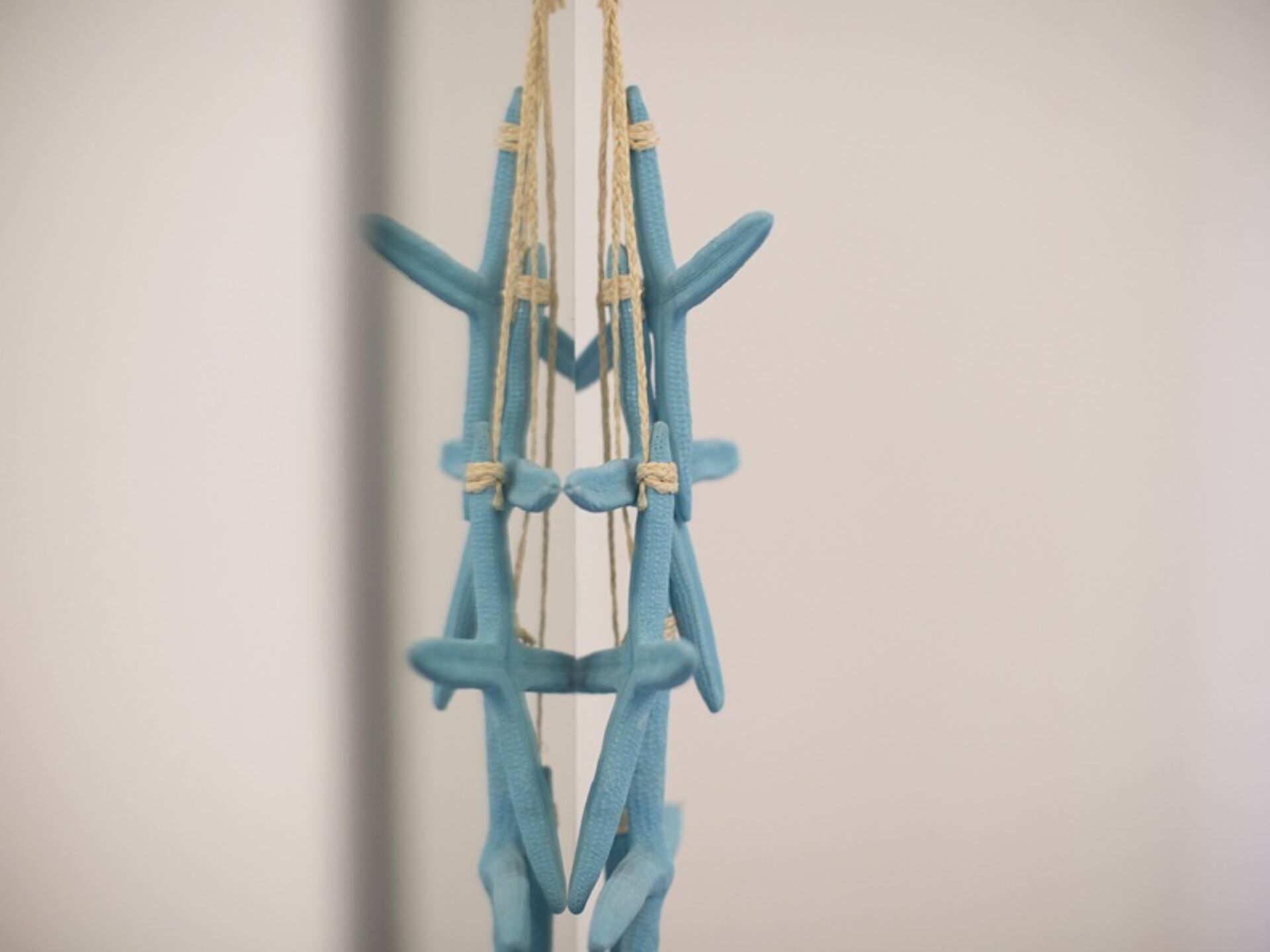 Eine Wanddekoration aus Makramee mit blau-beigen Kordeln.