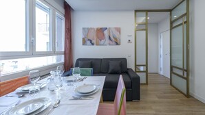 A modern dining area with a table set for six, a black sofa, and abstract art on the wall. - GRAN VIA capitals, LOS ANGElES (Madrid)