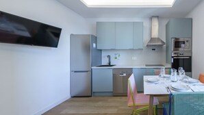 A modern kitchen with grey cabinets, a dishwasher, a microwave, and a dining area with a table set for two. - GRAN VIA capitals, LOS ANGElES (Madrid)