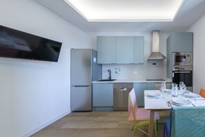 Eine moderne Küche mit grauen Schränken, einem Geschirrspüler, einer Mikrowelle und einem Essbereich mit Tisch für zwei Personen.