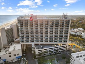 Ein Hochhaus-Hotel mit mehreren Stockwerken, einer Tiefgarage und Blick auf den Strand.