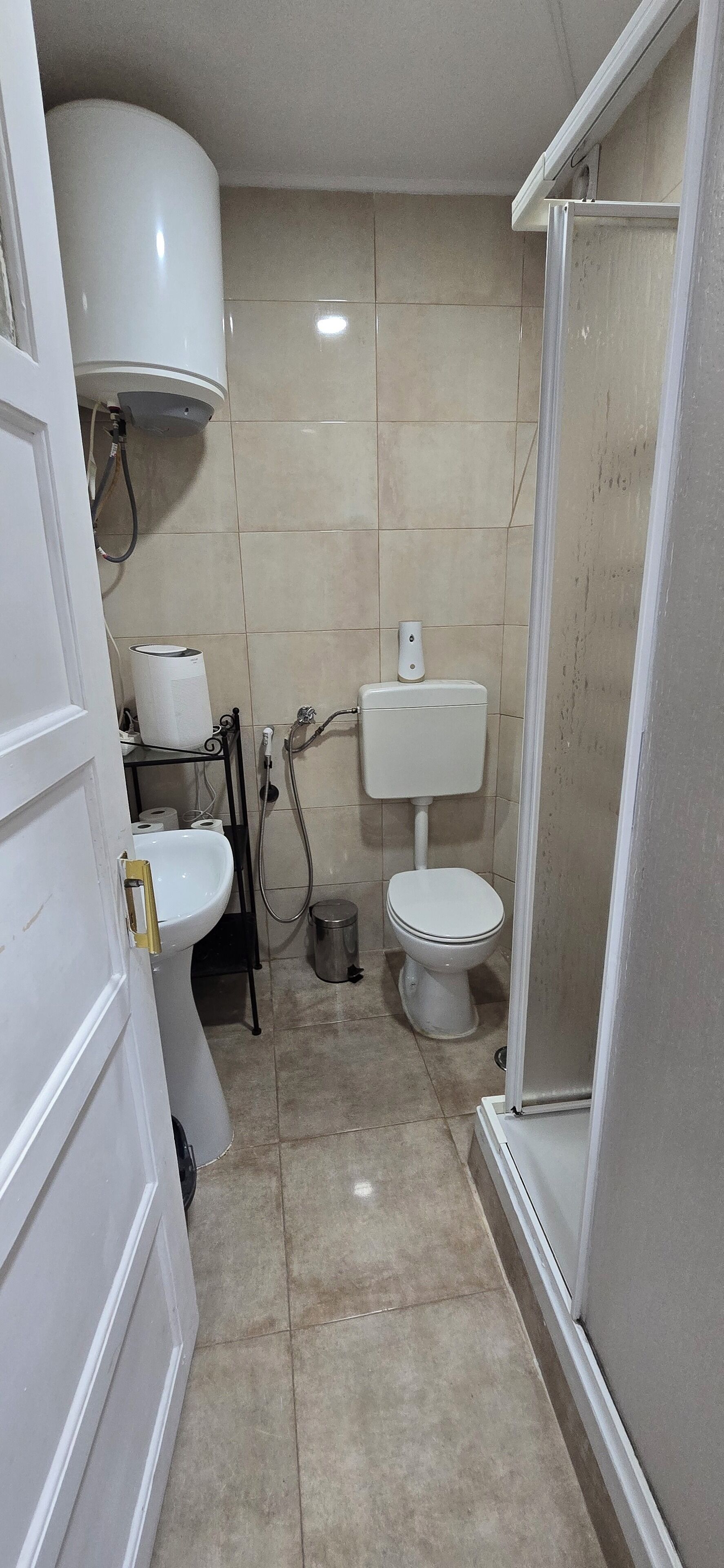 A small bathroom with a toilet, sink, and shower.