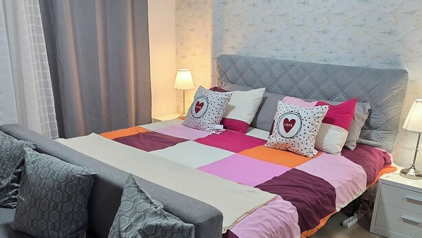 A bedroom with a bed, grey sofa, and a small white table. - Basement apartment studio in Lisbon Portugal, near the center. (Lisboa)