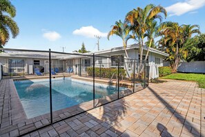 A swimming pool with a fence, lounge chairs, and palm trees. - Swaying Palms Unit 1: 2 BR 2 Bath Retreat, Near Beach, Heated Pool, Free Parking (Fort Lauderdale)