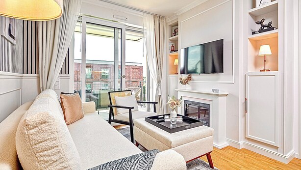 Una sala de estar moderna con sofá, sillón, mesa de centro, televisor de pantalla plana y chimenea.