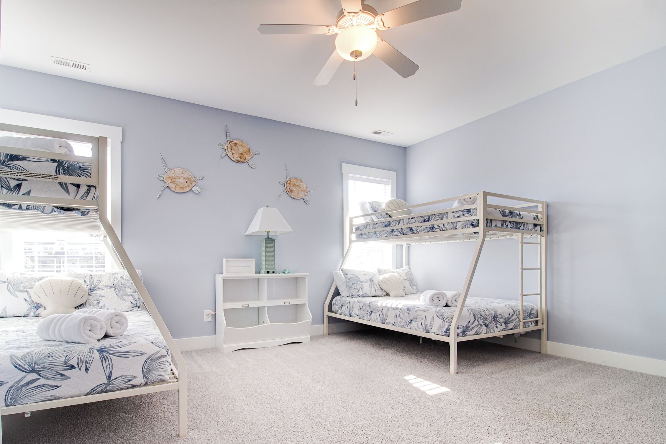 A child's bedroom with bunk beds, a ceiling fan, a window, and wall decorations.