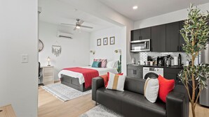 Um apartamento moderno com cozinha compacta, área de refeições e quarto com cama e escrivaninha.