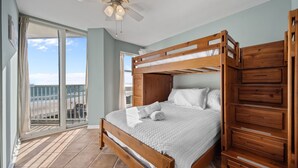 A bedroom with a wooden bunk bed, a ceiling fan, and a view of the beach through a sliding glass door. - Oceanfront Balcony Views at Dolphin Sightings (North Topsail Beach)