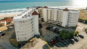 A multi-story hotel with a parking lot and ocean view. - Oceanfront Balcony Views at Dolphin Sightings (North Topsail Beach)