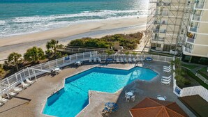 A swimming pool with lounge chairs and umbrellas, a beach view, and a building with scaffolding. - Oceanfront Balcony Views at Dolphin Sightings (North Topsail Beach)