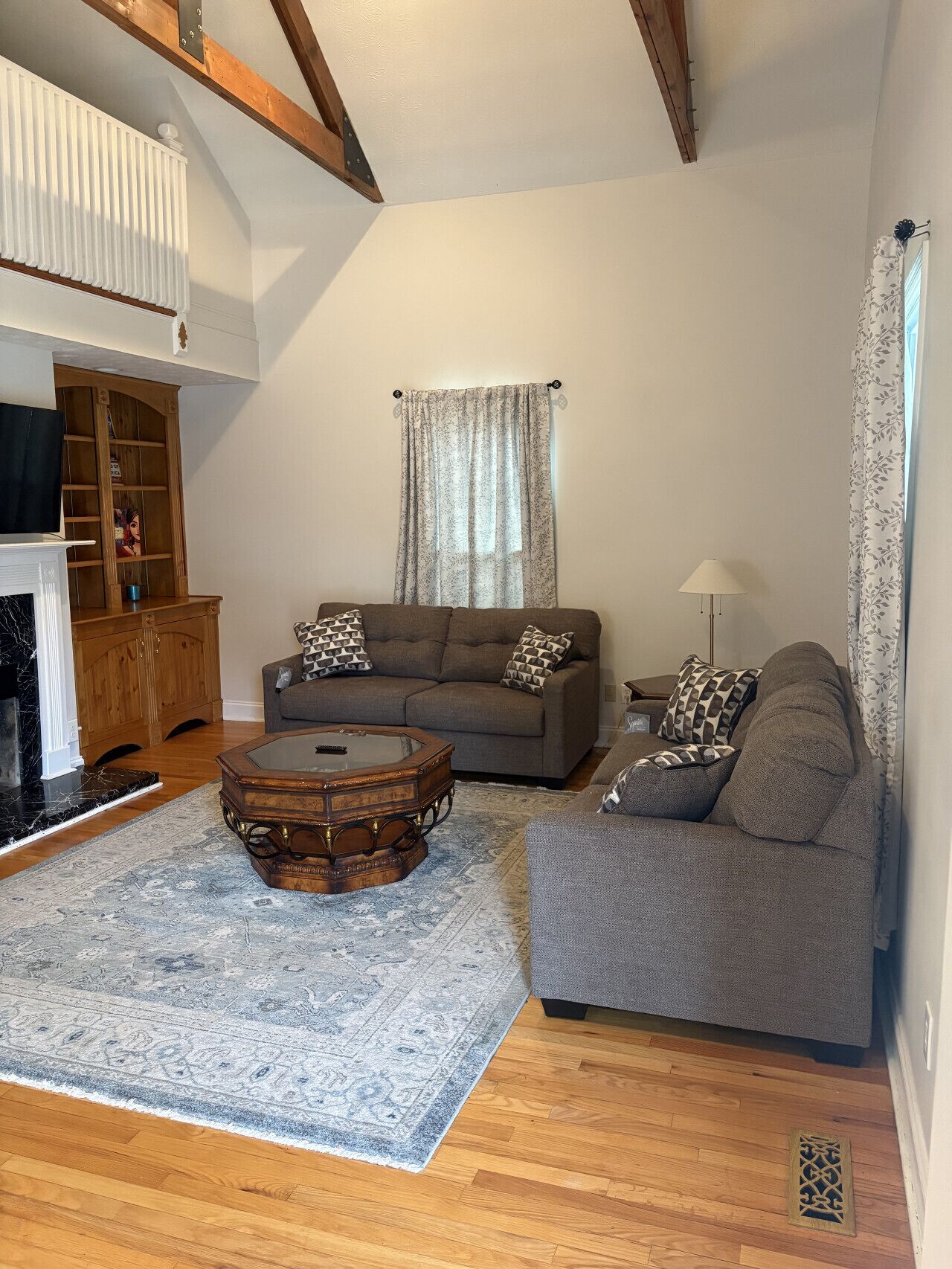 A living room with a sofa, a coffee table, a fireplace, and a wooden cabinet.