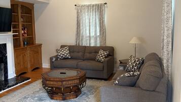 A living room with a sofa, a coffee table, a fireplace, and a wooden cabinet.