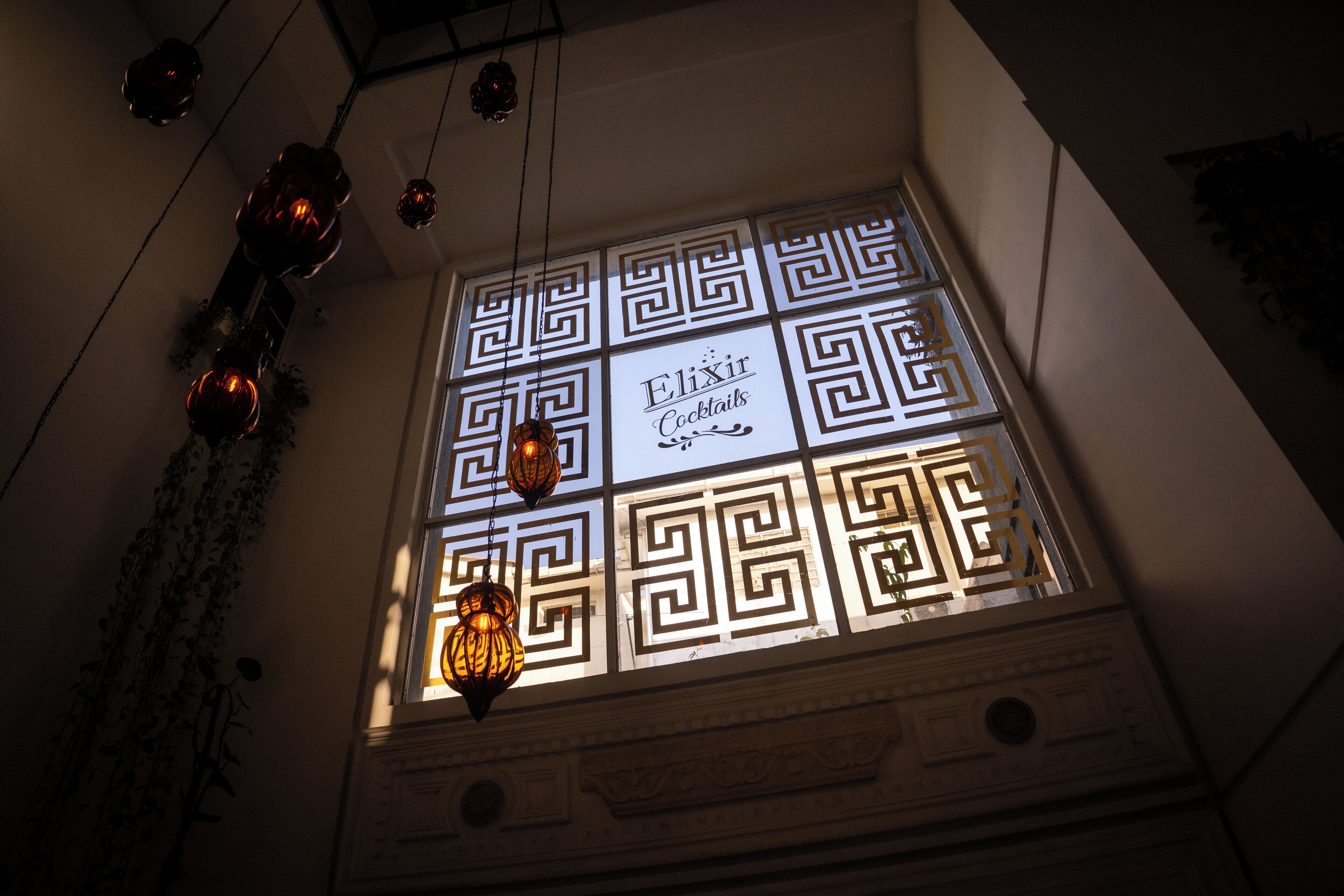 A window with geometric patterns and the text 'Elixir Cocktails' on it.
