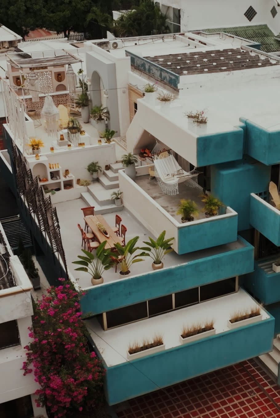 Een meerlaags gebouw met balkons, terrasjes en bloempotten.
