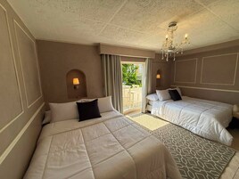 Habitación de hotel con dos camas, un candelabro y vistas al exterior.