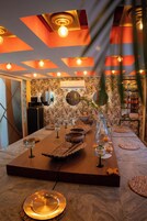 Un comedor con una mesa larga, velas y un jarrón con flores.