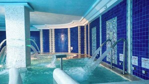 Un espace de bien-être comprenant un jacuzzi, des jets d’eau et des murs recouverts de carreaux bleus.