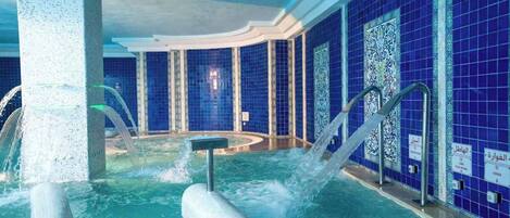A spa area with a hot tub, water jets, and blue-tiled walls.