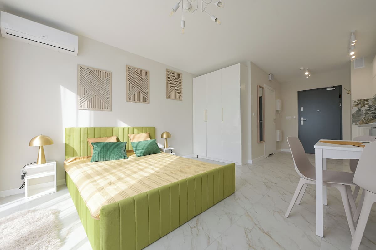 Een moderne slaapkamer met een groen bed, een bureau en een stoel.