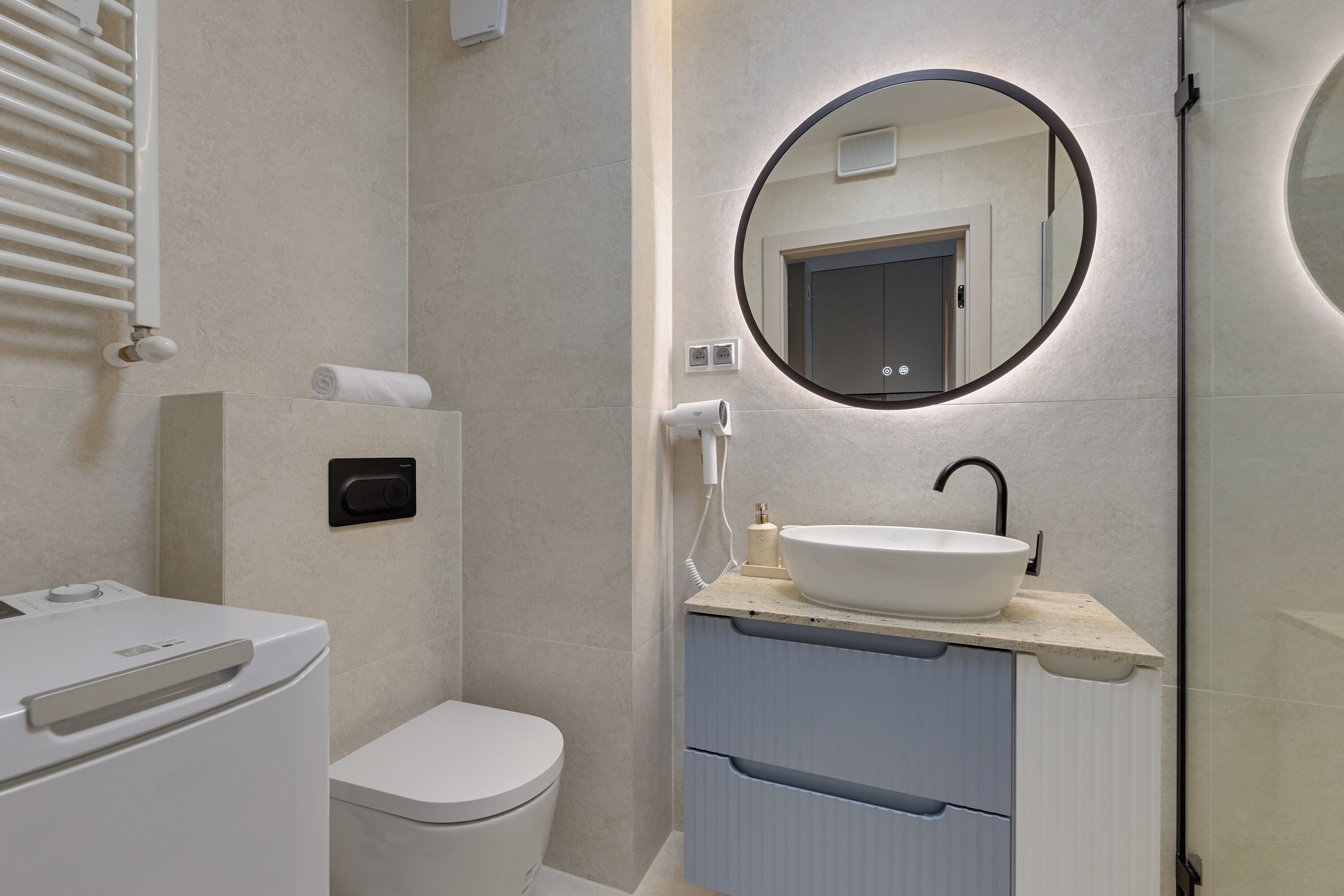 Ein modernes Badezimmer mit Toilette, Waschbecken mit Spiegel und Handtuchspender.