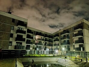 Un immeuble résidentiel à plusieurs étages, doté de balcons, d’une piscine et d’une cour bien éclairée.