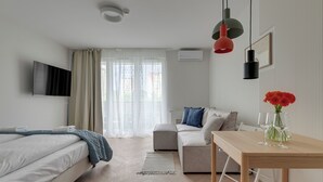 Ein modernes Hotelzimmer mit Bett, einer Couch, einem Esstisch und einem Fernseher.