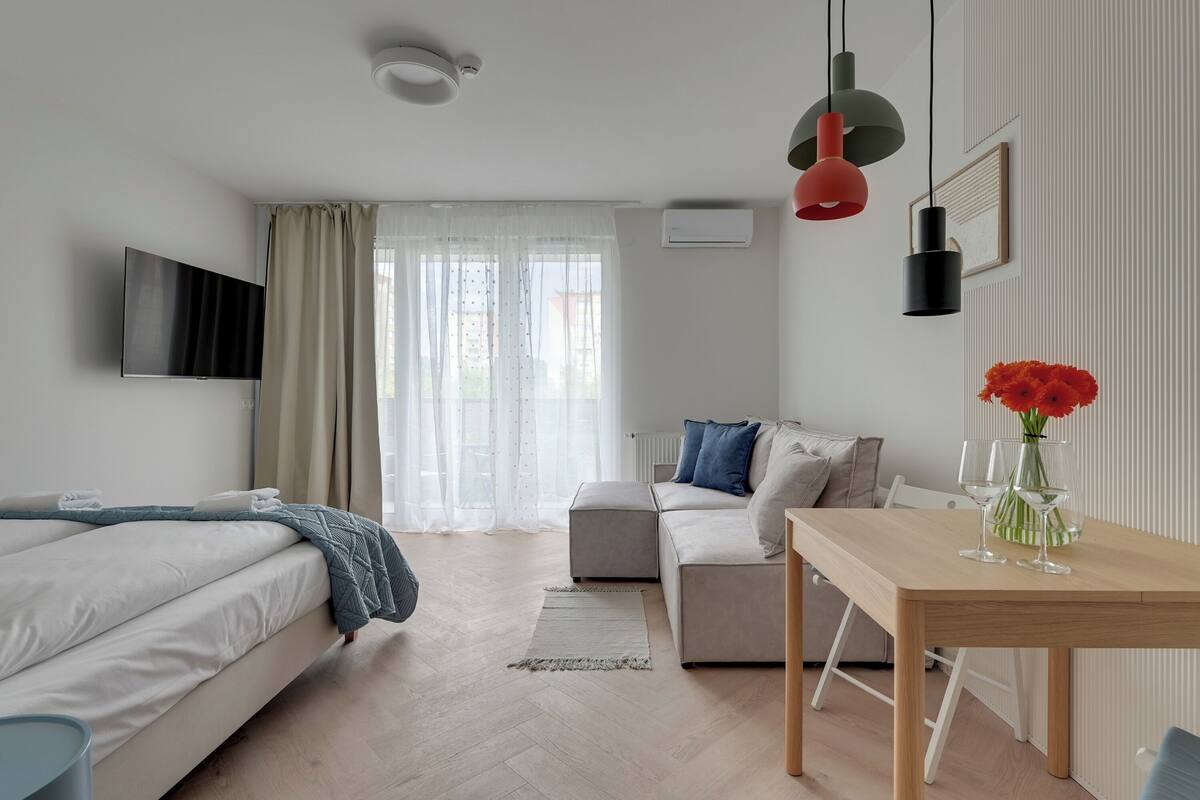 Een moderne hotelkamer met een bed, een sofa, een eettafel en een televisie.